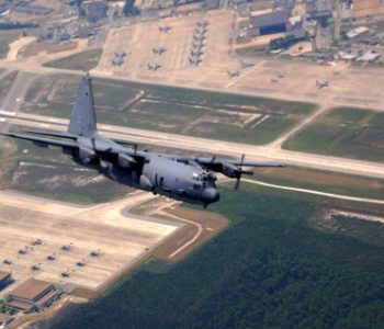 Aerial photo of a C-130 flying over the runway and tarmac at Hurlburt Field Air Force Base in Mary Esther, FL