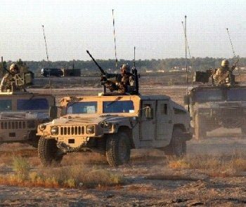 A HUMVEE with a soldier on top driving on the road at Red River Army Depot Army Base I in Bowie County, TX
