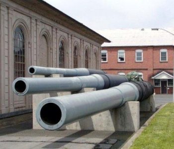 Decommissioned artillery barrels on static display in front of a large stone building at Watervilet Arsenal Army Base in Watervilet, NY
