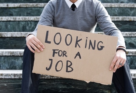 A person sitting on a bench holding a sign with the words Looking for a Job