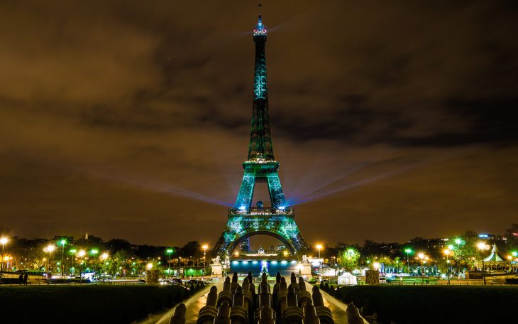 Image of the Eiffel Tower at night, lit with colorful spotlights