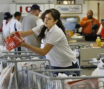 Employee packing grocery cart at Baumholder Commissary check out lane